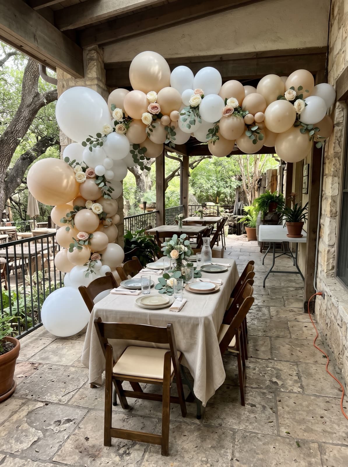 Floral balloon arch with roses and greenery over a brunch table