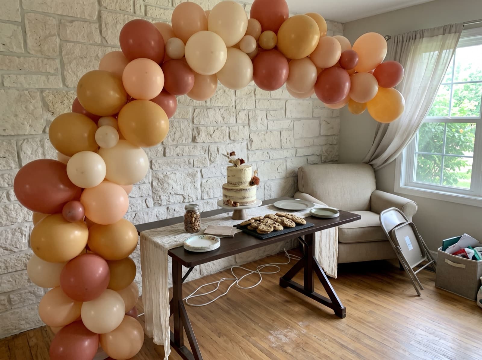 Organic balloon arch in terracotta, peach and cream over a dessert table