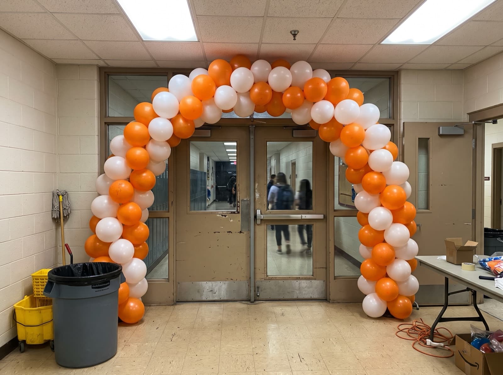 Spiral balloon arch in orange and white over school doors