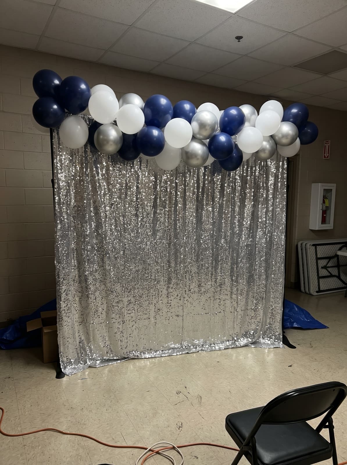 Silver shimmer wall backdrop with a navy and white balloon garland