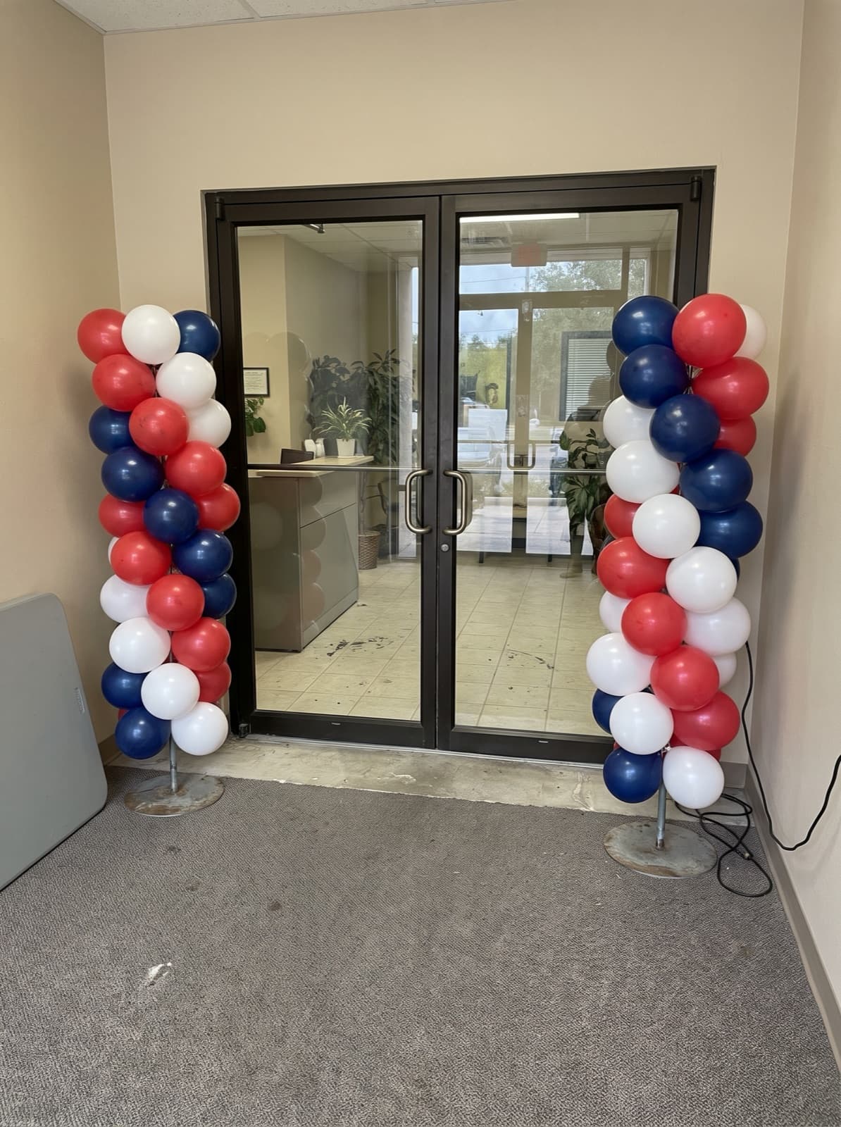 Red, white and blue spiral balloon columns at an office entrance