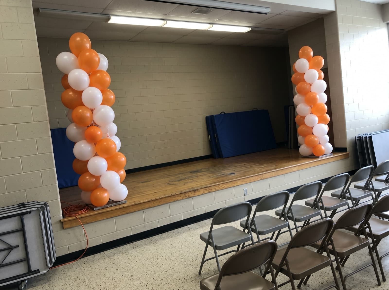 Tall orange and white balloon columns beside a stage
