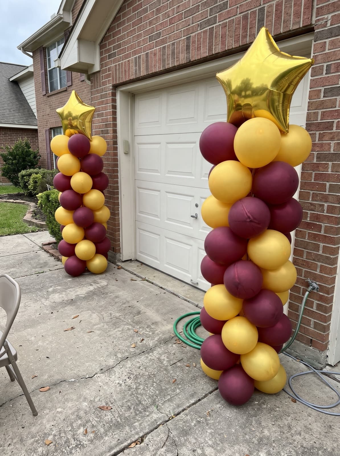 Maroon and gold balloon columns with star toppers for a graduation