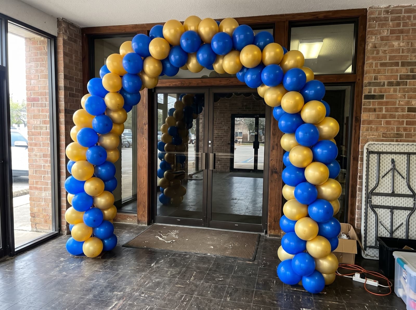 Balloon columns joined by a royal blue and gold arch