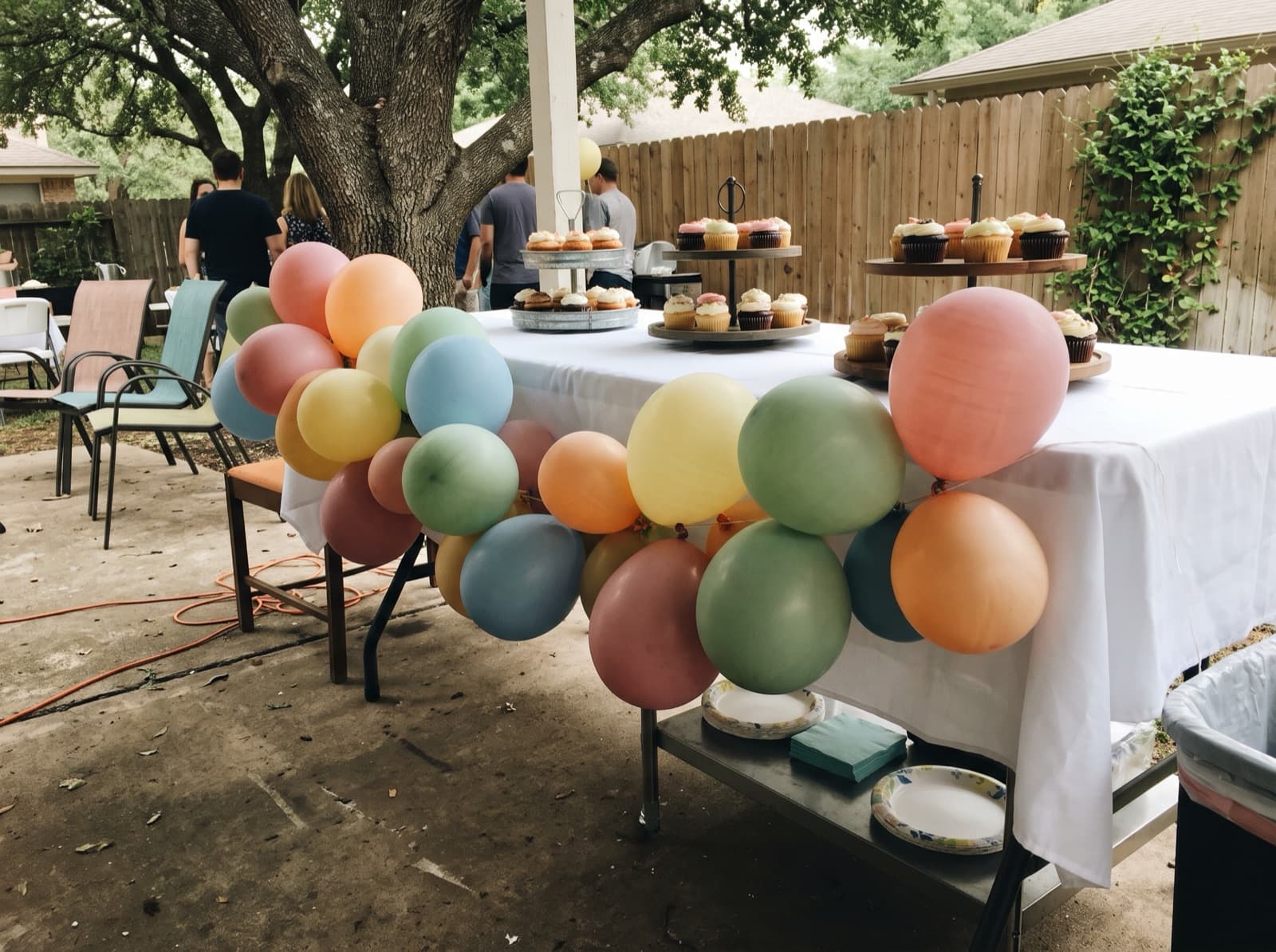 Pastel balloon garland along the front of an outdoor cake table