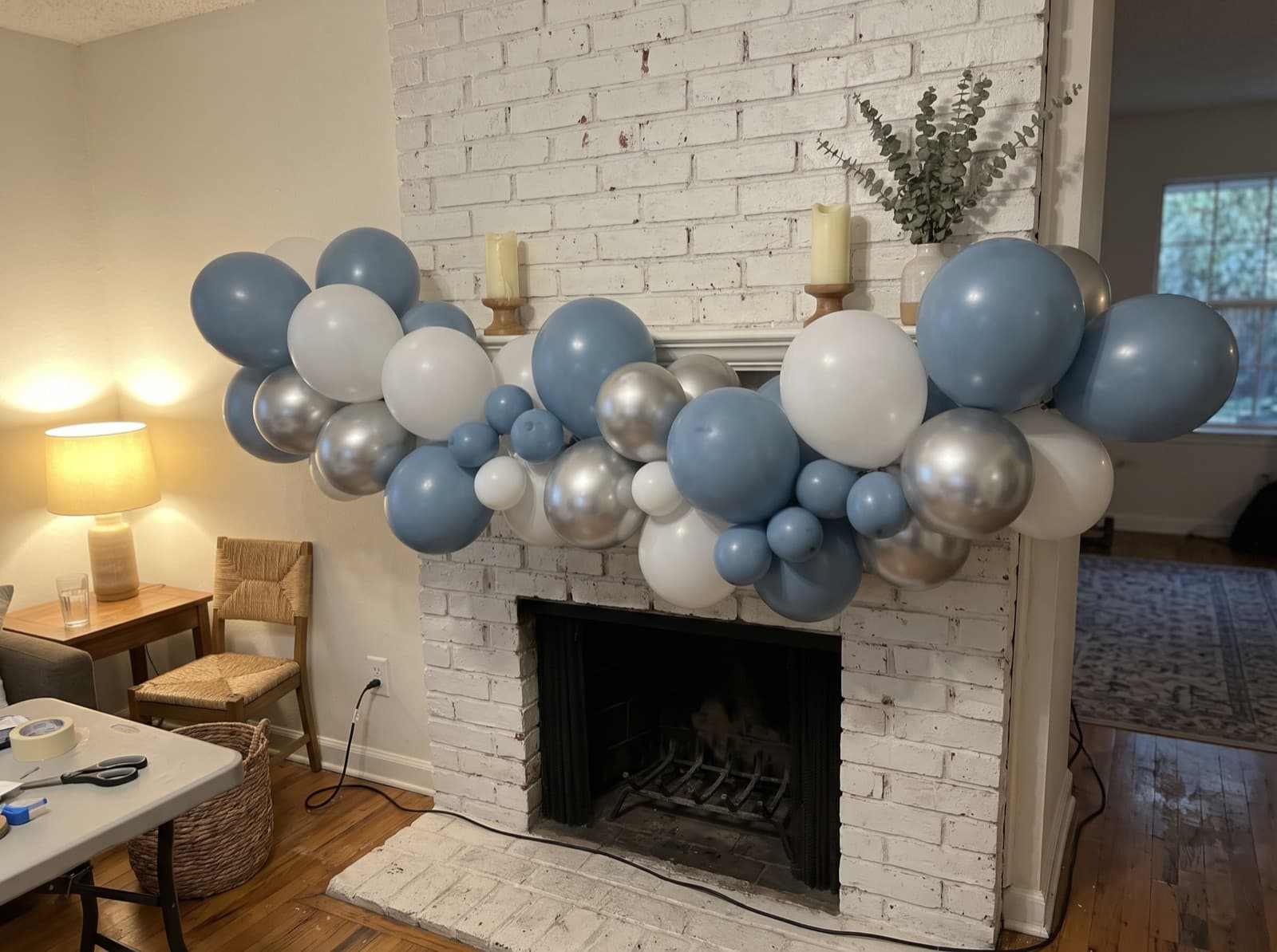 Organic balloon garland in dusty blue, white and silver along a brick mantel