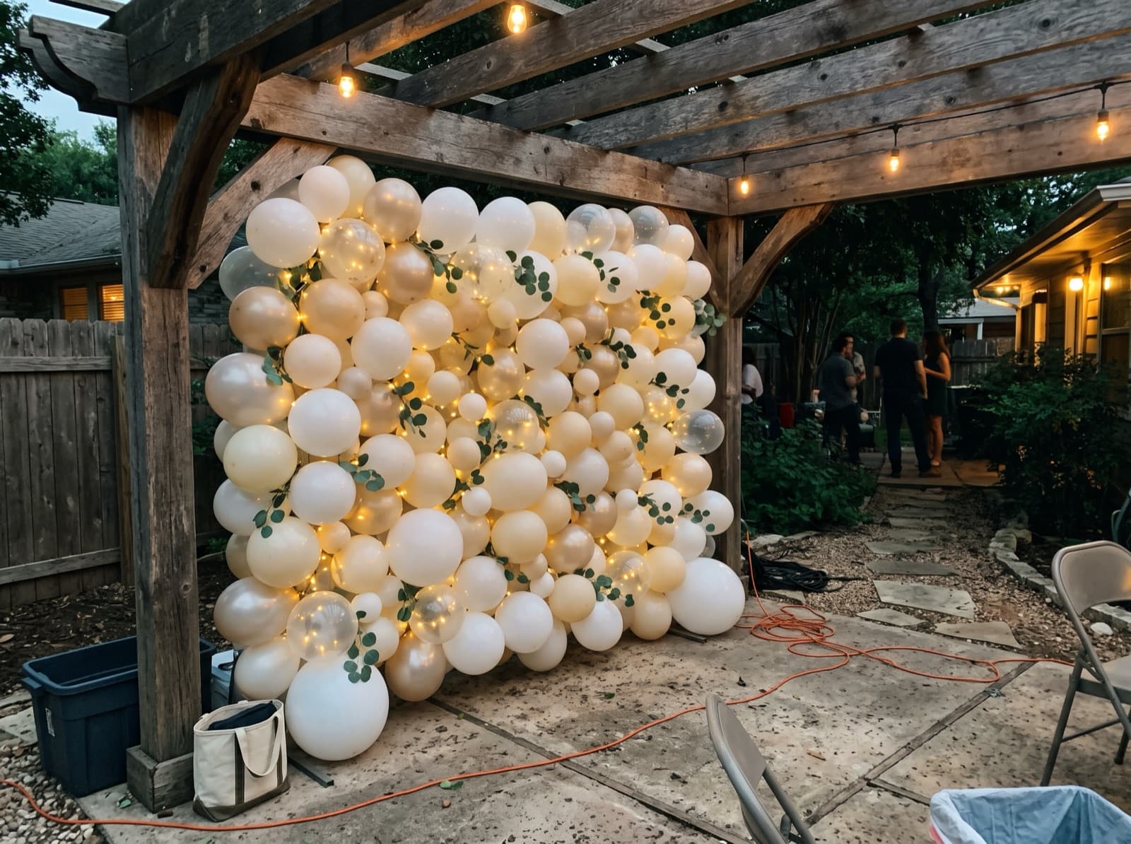 Balloon wall with string lights under a backyard pergola